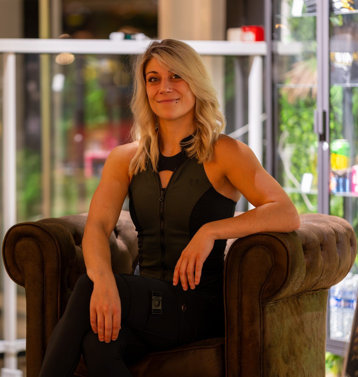 Portrait de Sabrina, coach sportive, souriante et assise dans un fauteuil